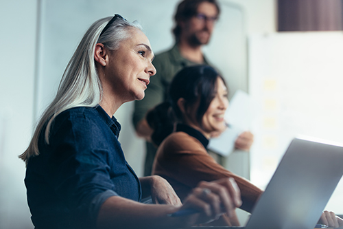 Woman on laptop with colleagues
