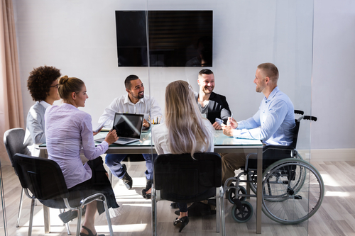 Few people with different characteristic talking around a meeting table about diverse and inclusive workforce