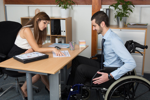 man using wheelchair talking to an officemate