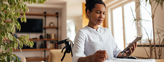 Picture of woman sitting in wheelchair in homeoffice taking the notes